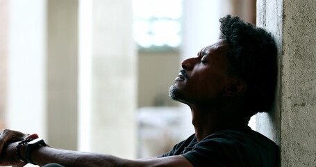 Pensive black man sitting on floor during hard difficult times - Powered by Adobe
