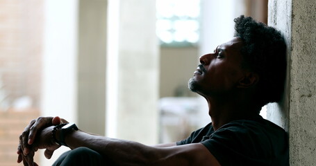 Pensive black man sitting on floor during hard difficult times