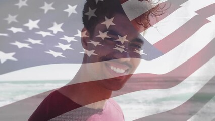 Animation of flag of united states of america over smiling biracial man on beach - Powered by Adobe