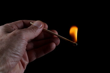 Match stick ignited burning bright big fire flame  in hand isolated on black