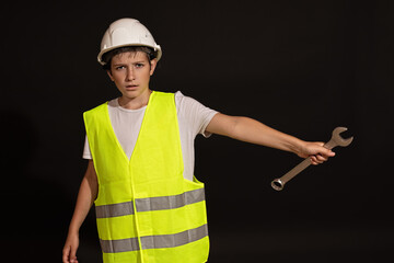 A boy in a construction worker's suit with a wrench.