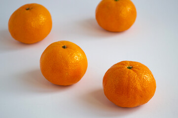 Four tangerines lying in a chaotic order. Orange fruits on a light background