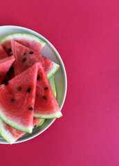 Ripe and sweet watermelon pieces on red backrgound. Top view. Copy space. Summer enriched or vitaminized vegan food