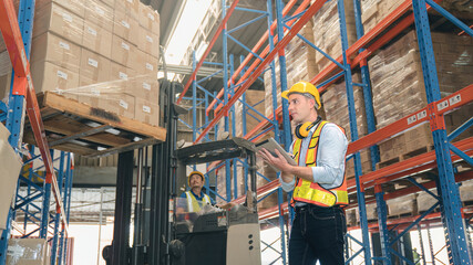 Smart caucasian warehouse man,manager use digital tablet check package with worker forklift driver...