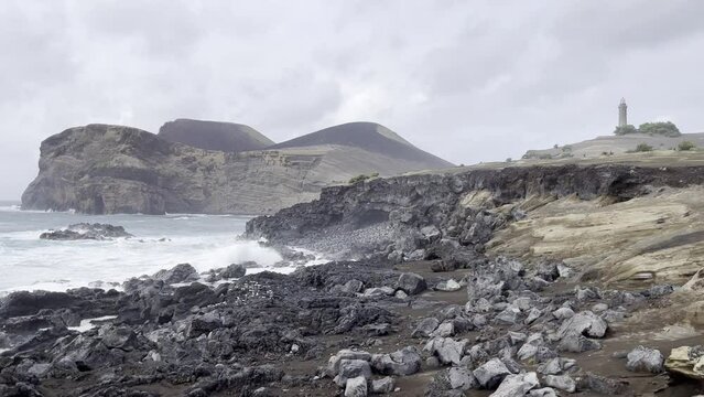 waves crashing on rocks in front of capelins on Faial island, Azores, Portugal