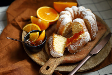 Soft and fluffy orange cake with powdered sugar on a wooden board.