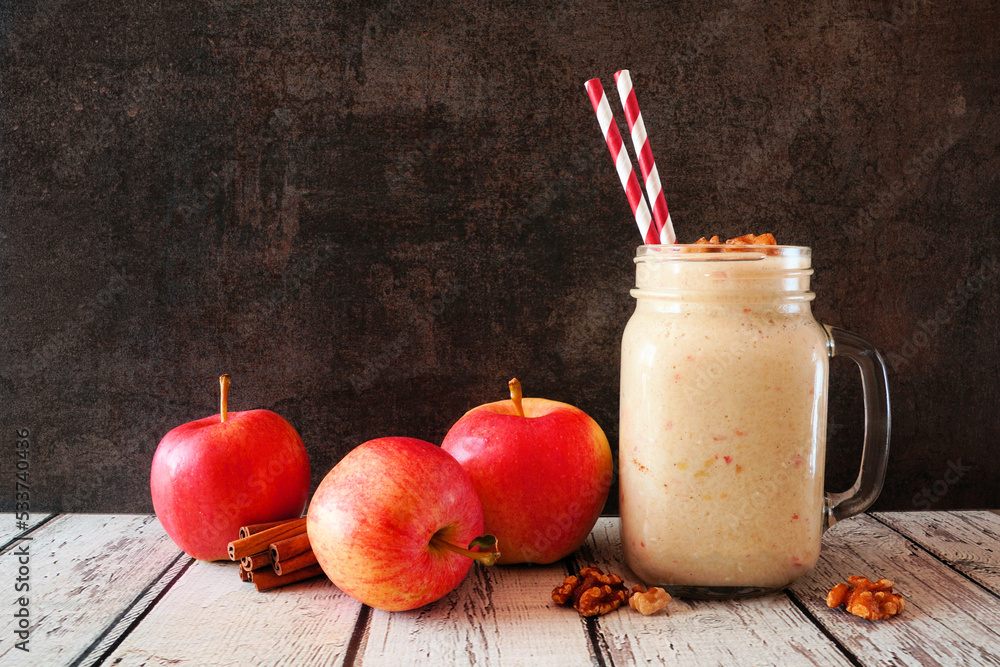 Wall mural apple pie smoothie in a mason jar with walnuts and cinnamon. side view scene on a dark background.