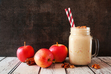 Apple pie smoothie in a mason jar with walnuts and cinnamon. Side view scene on a dark background.