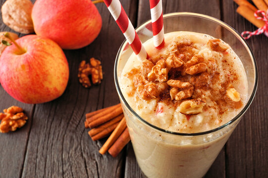 Apple pie smoothie close up in a glass with walnuts and cinnamon. Table scene on a rustic dark wood background.