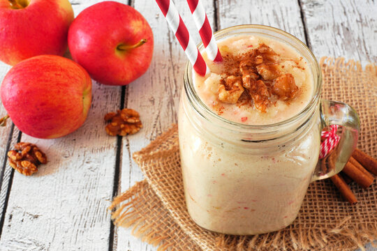 Apple pie smoothie in a mason jar with walnuts and cinnamon. Table scene on a rustic white wood background.