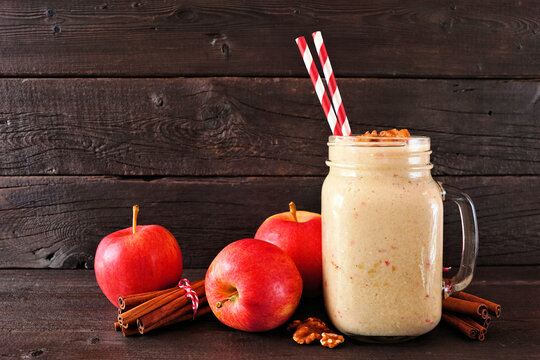Apple pie smoothie in a mason jar with walnuts and cinnamon. Side view scene on a dark wood background.