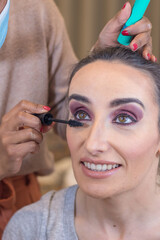 Young woman getting make-up indoors. Makeup service for special moments. Woman applying mascara. Process Steps. Close-up. 