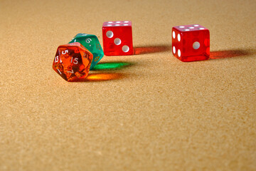 Four transparent dice, three red and one green giving a reflection on a table.