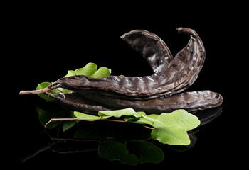 Carob. Healthy organic sweet carob pods with seeds and leaves close up. Healthy eating, food background. Organic vegan food. isolated on black background 