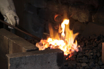 Ein Schmiedeeisen im glühenden Kohlenfeuer in einer Schmiedewerkstatt