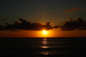 Salida del sol en el horizonte marino con nubes