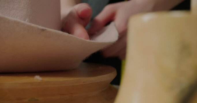 Hands of woman stretch material of felt hat to make brim