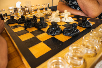 Traditional Georgian dish, khinkali Kalakuri, on wooden table, chess board, rustic, side view, black and light dough, playing chess. Selective focus, side view. Meat and cheese dishes