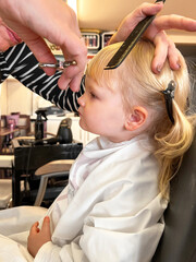 little blonde girl having a haircut in a salon