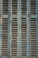 Texture of an old weathered wooden shutter. Close-up of a closed wooden window in grey-blue-brown. wooden slats.