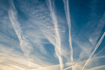 Pattern of several aircraft contrails in the sunset sky - obrazy, fototapety, plakaty