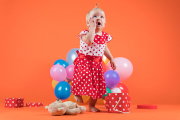 Crying baby girl in red dress upset with birthday gifts.