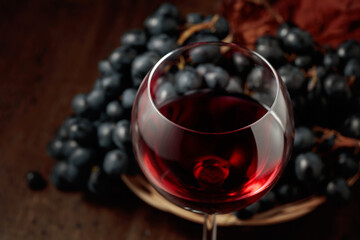 Red wine and blue grapes on an old wooden table.