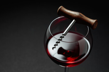 Glass of red wine and corkscrew.