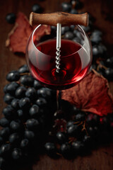 Red wine, corkscrew, and blue grapes.
