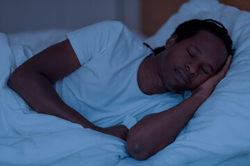 Portrait of young african american man sleeping in bed in the night