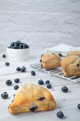 Freshly baked blueberry scones cooling on a rack on a marble countertop 