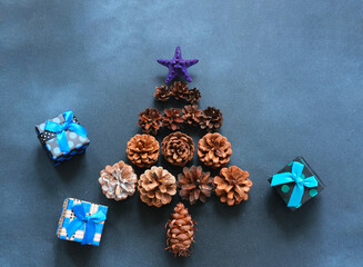 Christmas tree made of pine cones and gift boxes on dark blue background. New year Color Trends, Attention-grabbing Palettes 2023 year. DIY jewelry. Close-up