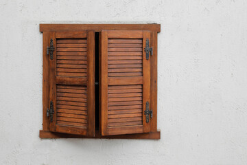 Window with closed wooden shutter,
white stone house wall, no person