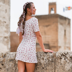 Fashion model with fancy hair style posing in white mini dress outside.