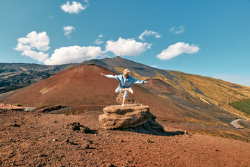 Happy tourist woman enjoying freedom while doing yoga on big stone at panoramic view of colorful...