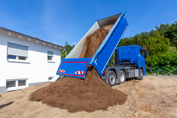 unloading the truck with potting soil from the truck bed at the construction site