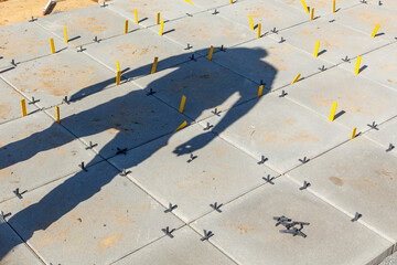 shadow of worker at the tiles of the veranda on the construction site - obrazy, fototapety, plakaty