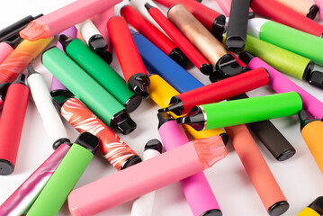 Set of colorful disposable electronic cigarettes of different shapes on a white background. The...