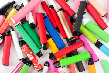 Set of colorful disposable electronic cigarettes of different shapes on a white background. The...