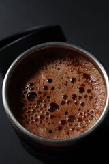 a thermo cup of cappuccino coffee on a black background