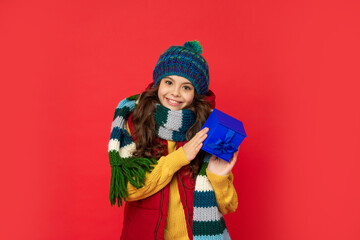 cheerful child in winter clothes hold box on red background, boxing day