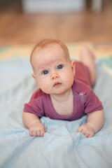 Close-up portrait of a cute Caucasian newborn baby. Charming funny baby baby looking into the camera. An authentic childhood and a candid lifestyle moment.