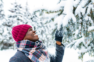 happy carefree african american man in warm clothes taking a deep breath in fir forest