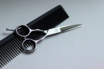 scissors and comb on a white background.black comb and silver scissors.silver scissors on a white background.barber tools.hairdresser