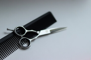 scissors and comb on a white background.black comb and silver scissors.silver scissors on a white background.barber tools.hairdresser