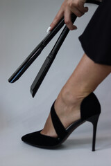 girl holding a curling iron at her leg.curling iron.black curling iron close-up.girl holding a curling iron in her hand