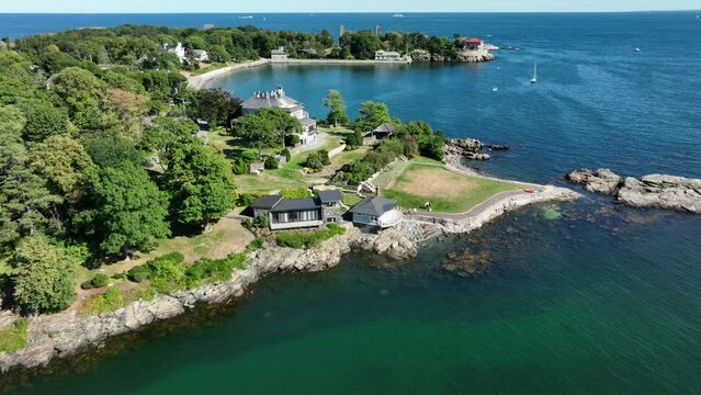 Aerial drone footage of Nahant, Massachusetts near Boston. Beautiful blue sky, green forest and waves crashing on the rocky shore of the Atlantic Ocean during summer.