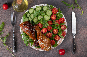 Baked chicken drumsticks with cherry tomato, cucumber and arugula salad, Top view