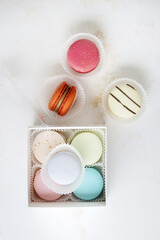 Colorful macaroons in a gift box on a white table. Very soft pastel colors.