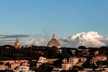 Fototapeta na wymiar Panorama of Rome, view of the dome of St. Peter and the Vatican walls. Residential buildings in the foreground and large white clouds in the background.